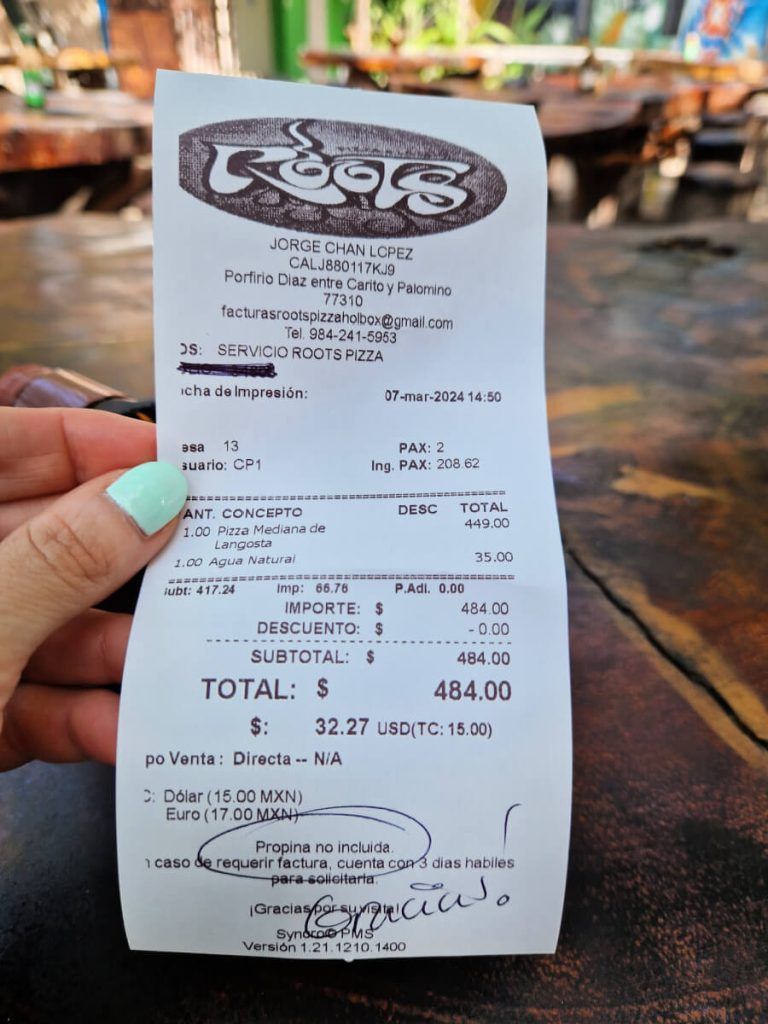 A restaurant bill from Roots Pizza in Holbox shows a total of 484.00 Mexican pesos with handwritten notes indicating that the tip is not included.