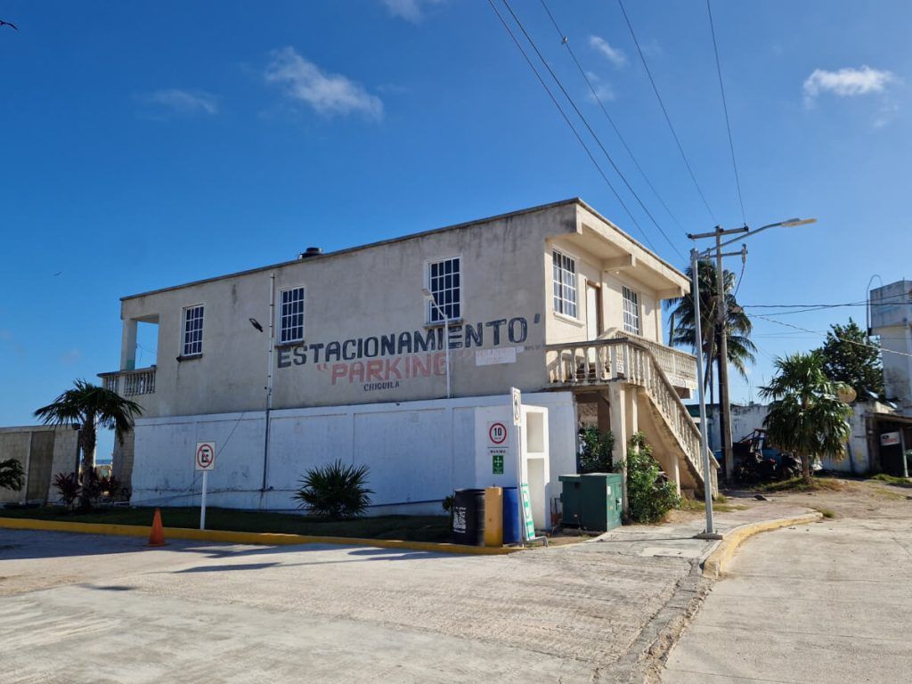 Parking lot in Chiquila, indicated by 'Estacionamiento Parking' sign on a two-story building.