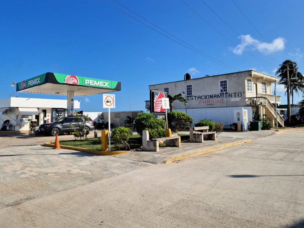 PEMEX gas station adjacent to 'Estacionamiento Parking' facility in Chiquila, showcasing a clear day and palm trees in the vicinity.